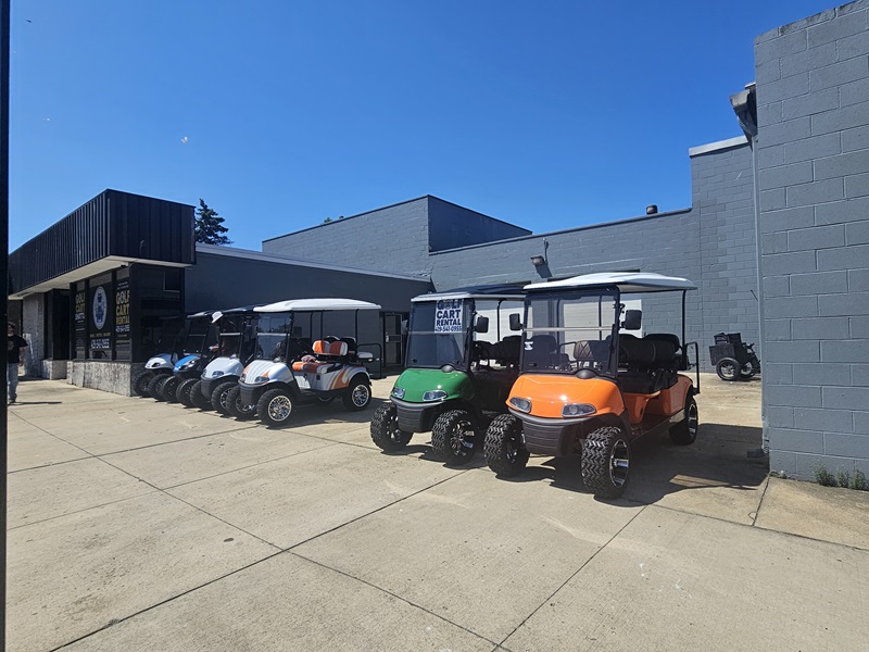 View of golf carts of different colors lined up along the building wall