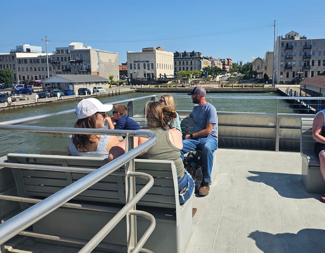 View of the seats on the outdoor deck of the ferry, with the surrounding downtown area in the background