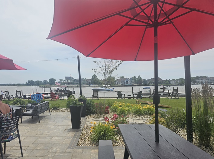 Close-up view of Pipe Creek Wharf's patio, focusing on the lawn games, the waterfront lounge chairs, and the view across the bay