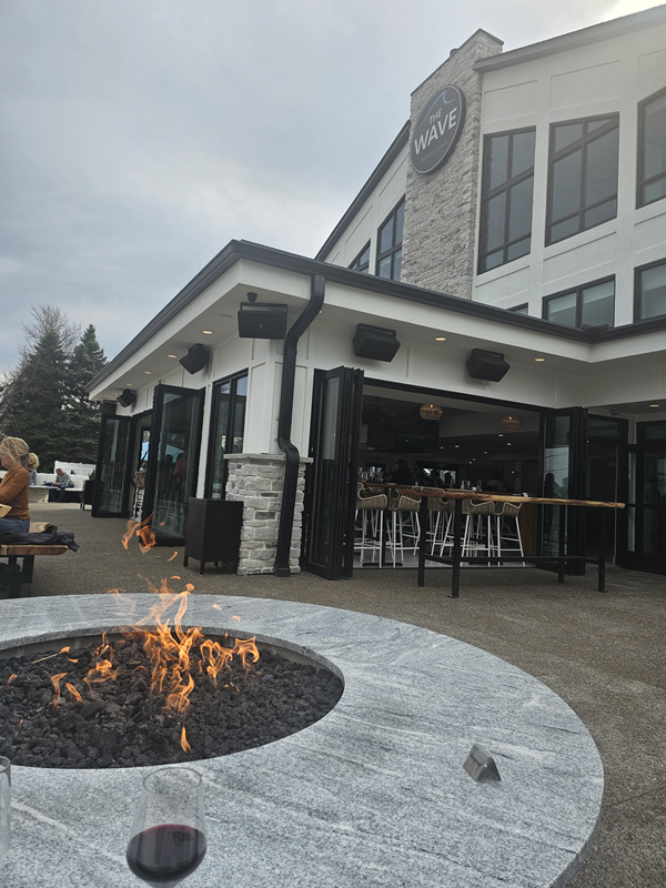 Patio table with a firepit in the center, with the view of the restaurant building to the right