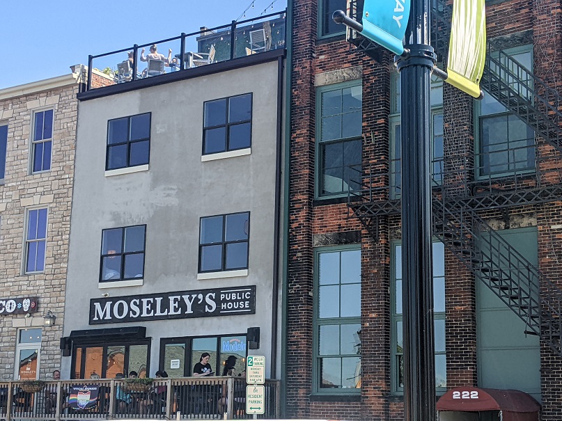 Back of Moseley's Rooftop Bar building with a large Moseley's sign and a view of the rooftop bar above